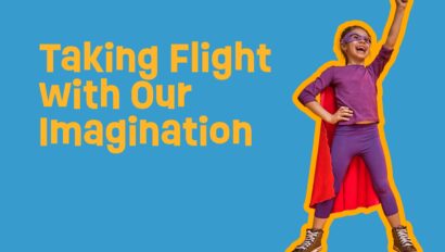 Child wearing a cape and posing like a super hero.